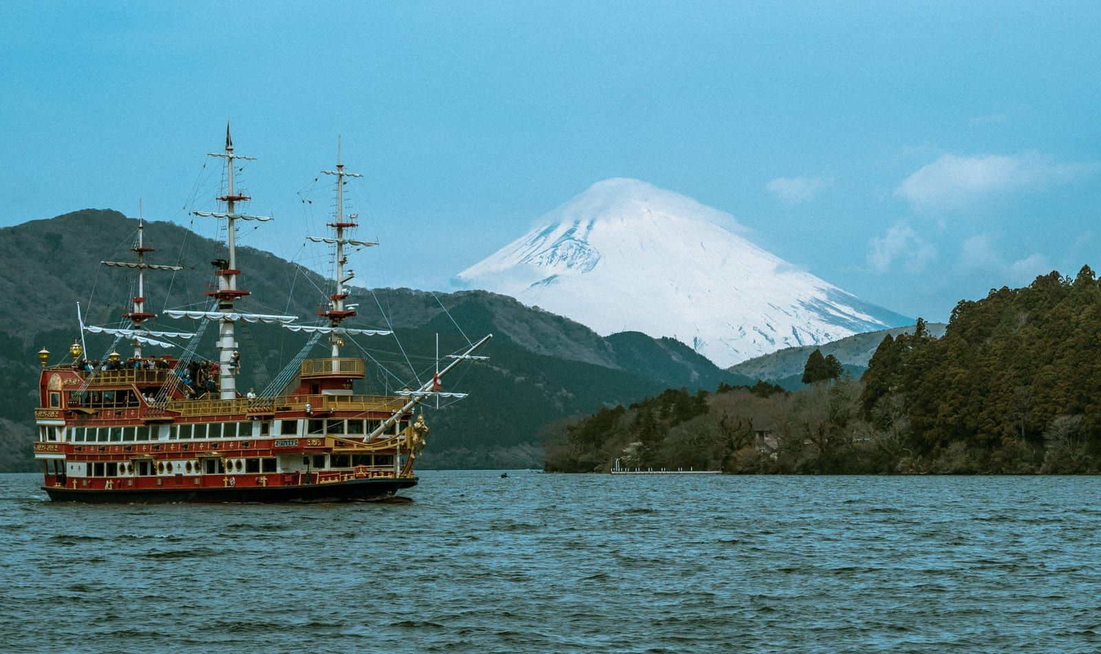 A Hakone sightseeing cruise pirate ship on Lake Ashi with snow-capped Mount Fuji behind the hills