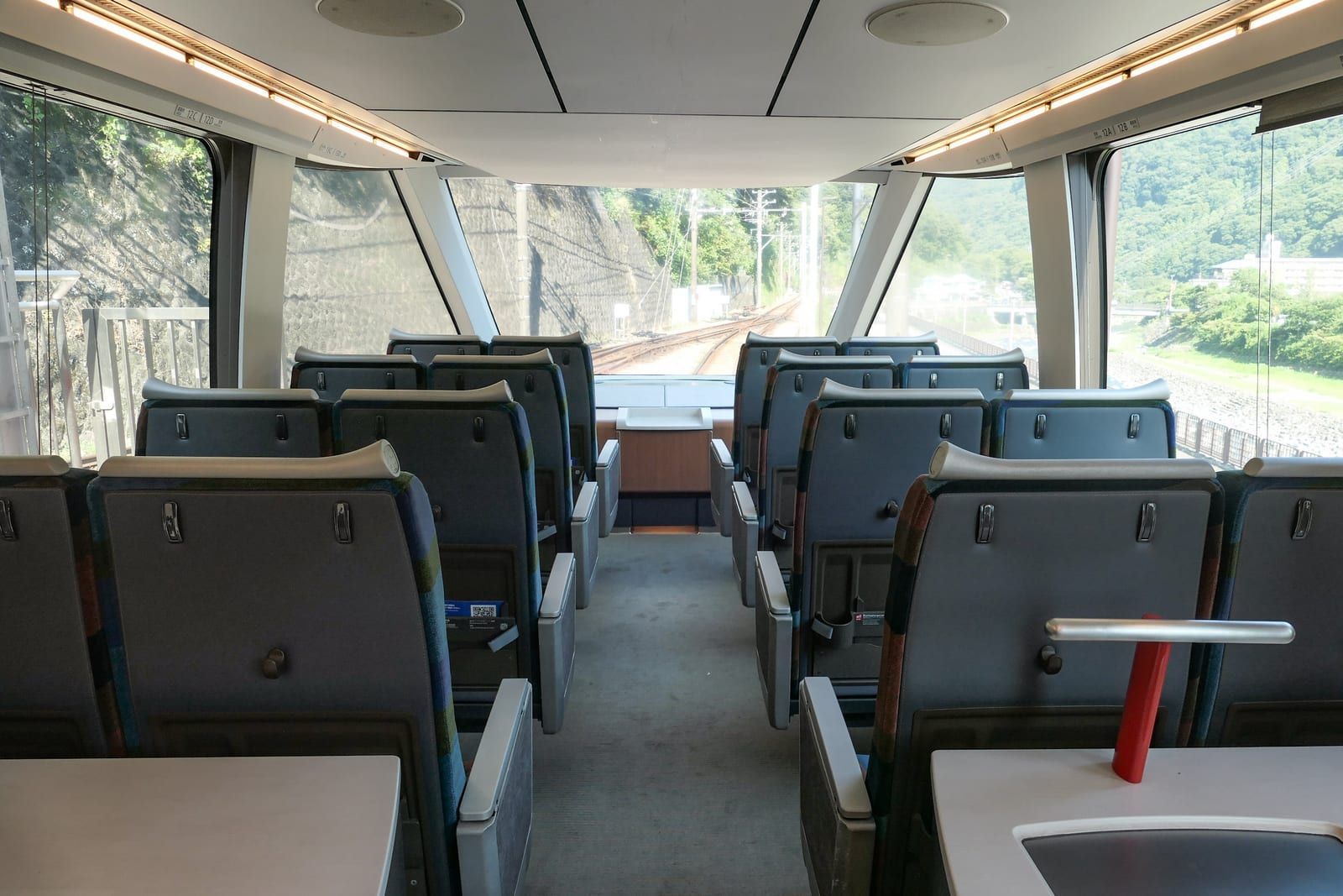 Empty observation seats at the front of a Romancecar, with the track curving ahead through the wide front window