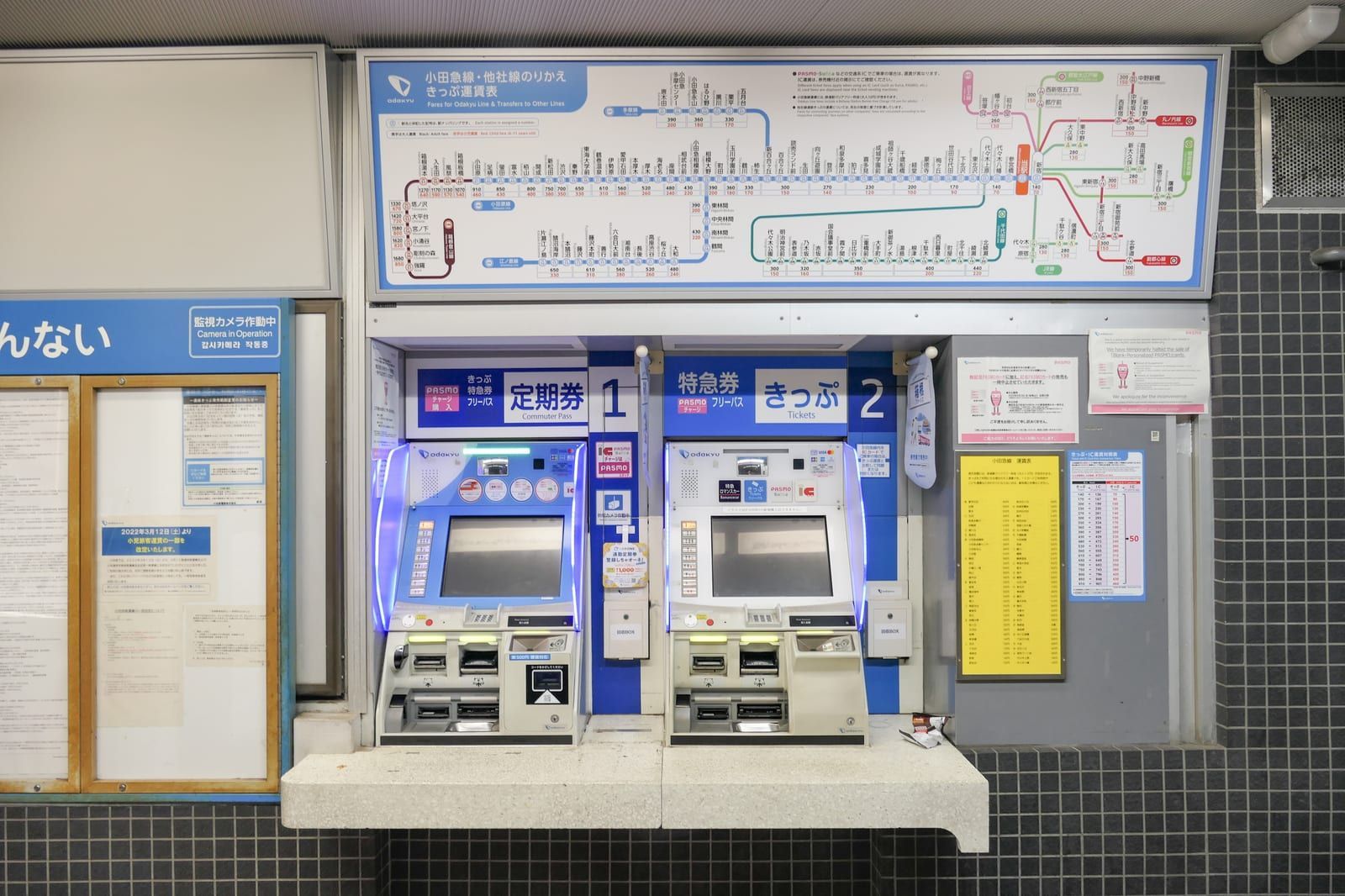 Two Odakyu ticket machines for limited express and regular tickets under a fare map