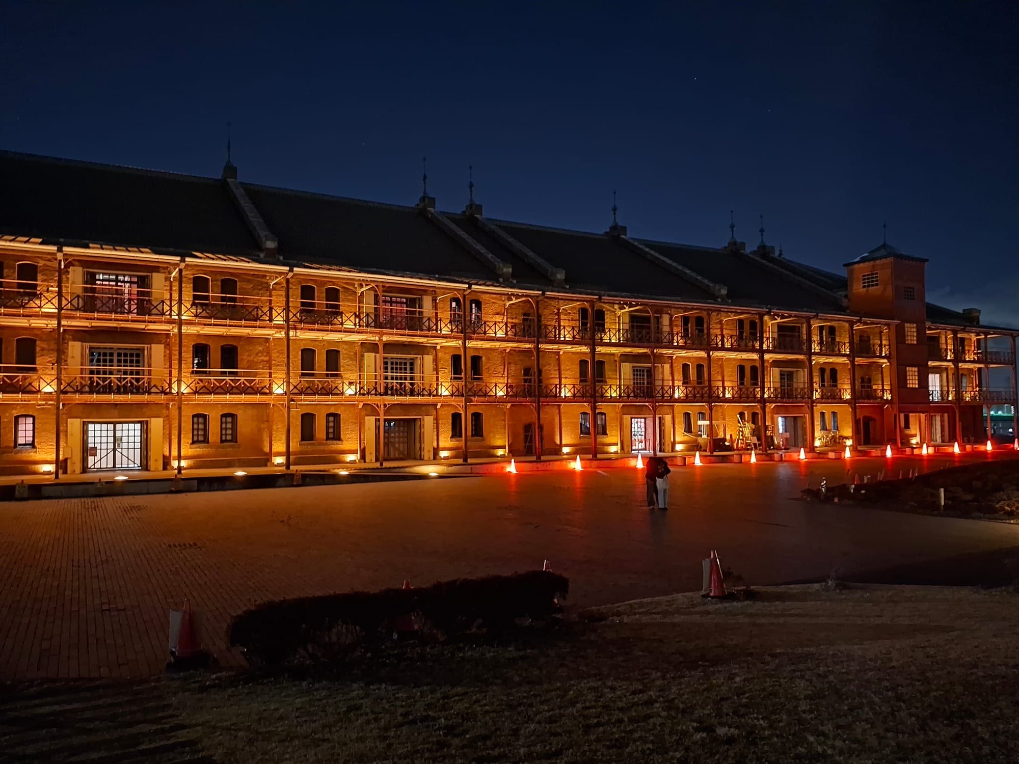The long brick facade of the Yokohama Red Brick Warehouse lit up in warm light at night